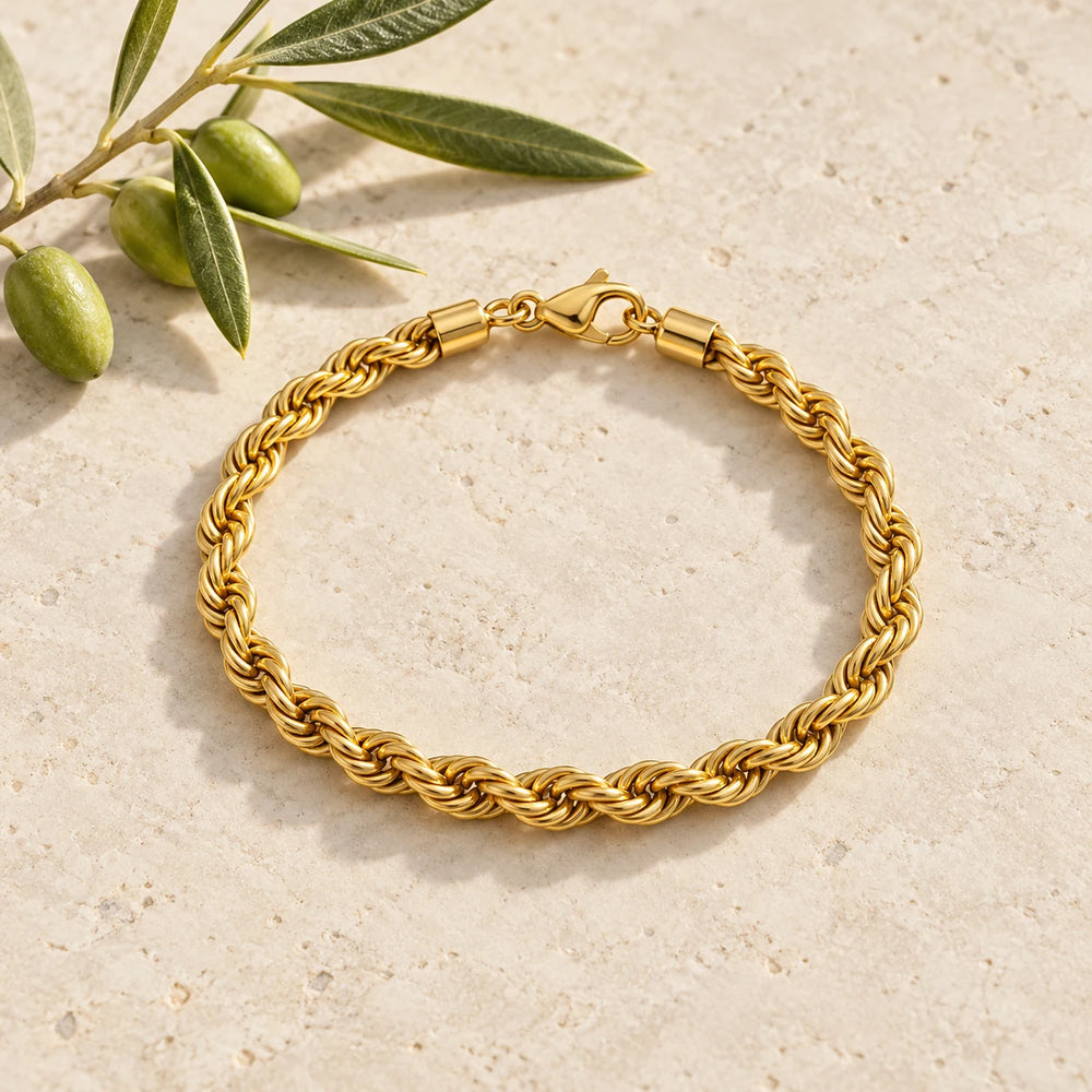 Gold-tone 5 mm rope chain bracelet on a pale limestone background, with an olive sprig for scale — true size: the twisted rope bracelet is 5 mm thick, 21 cm long