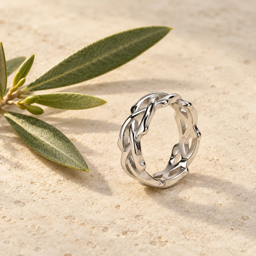 Silver-tone woven crown of thorns ring on a pale limestone background