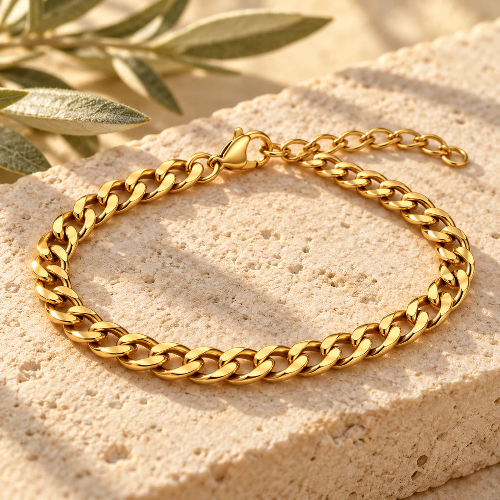 Close-up of the gold-tone 4 mm cuban chain bracelet on limestone beside olive leaves