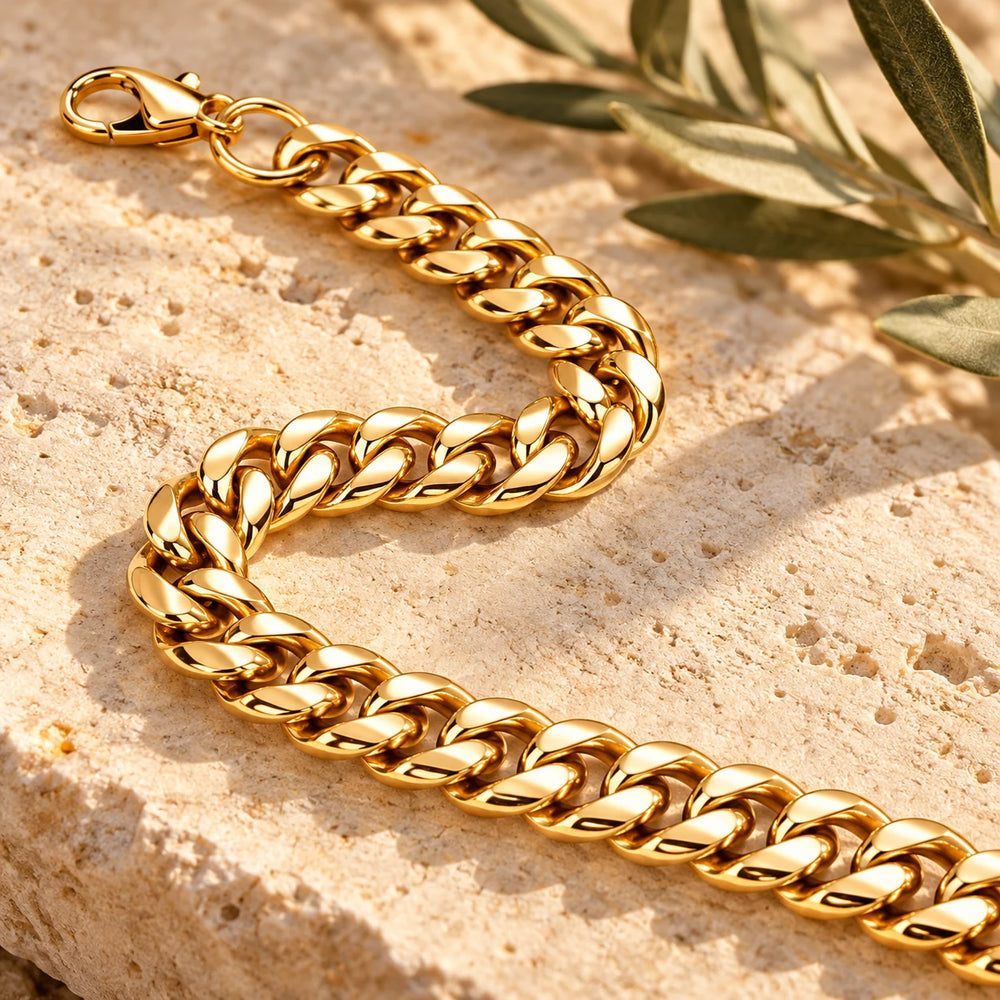 Close-up of the gold-tone 8 mm cuban chain necklace on limestone beside olive leaves