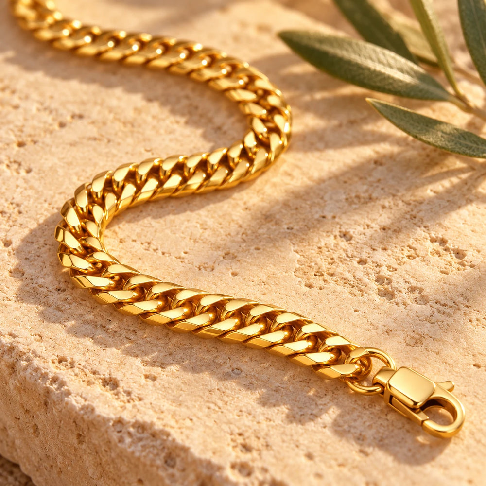 Close-up of the gold-tone 6 mm cuban chain necklace on limestone beside olive leaves