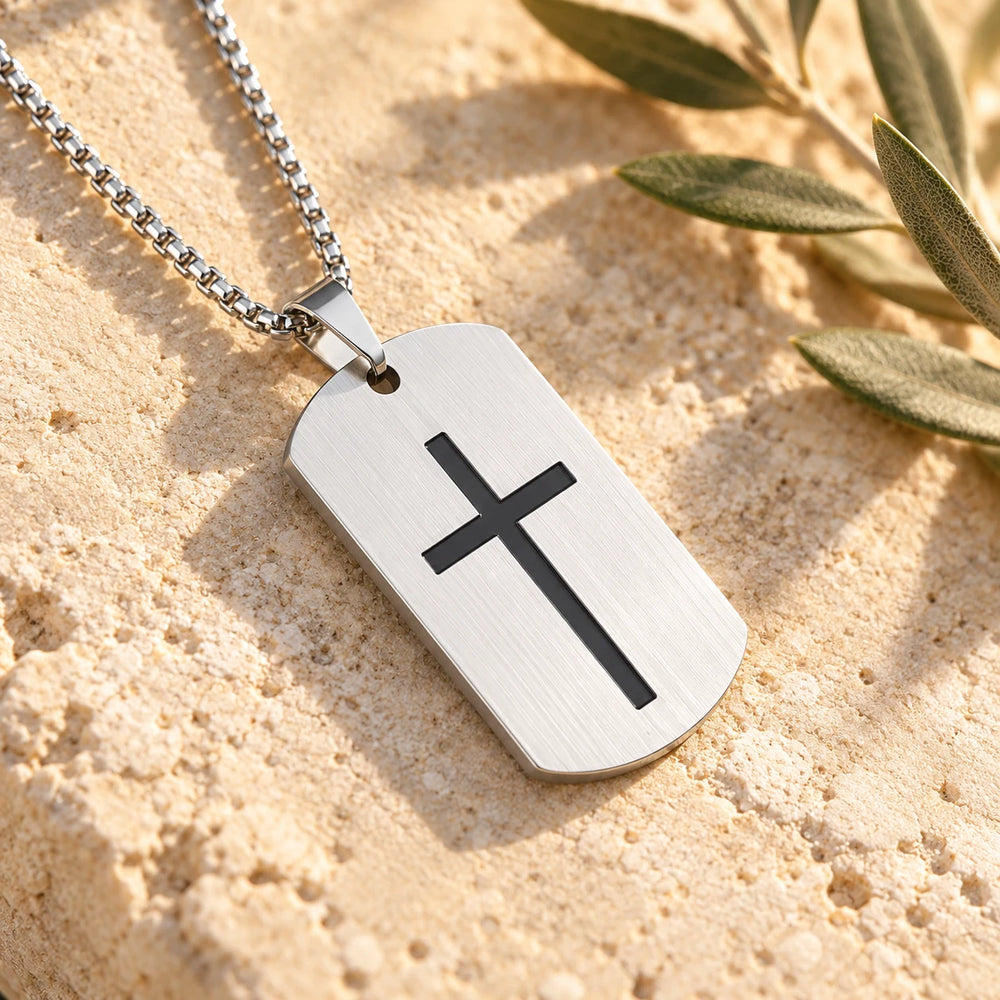Close-up of the silver-tone cross tag on limestone beside olive leaves