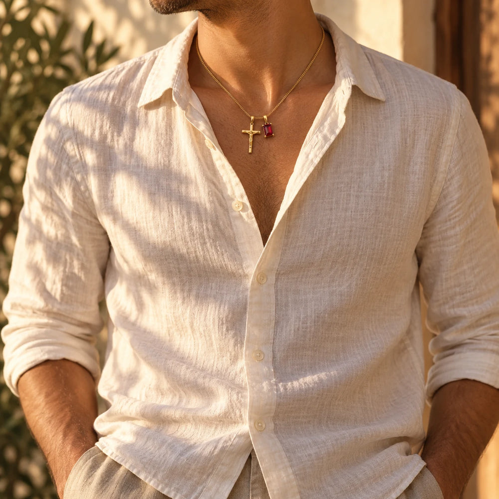 Gold-tone crucifix and red stone pendants worn with an open linen shirt — true size: the small cross is about 22 mm tall and hangs beside a rectangular stone about 10 × 8 mm, on a fine curb chain about 1.2 mm wide