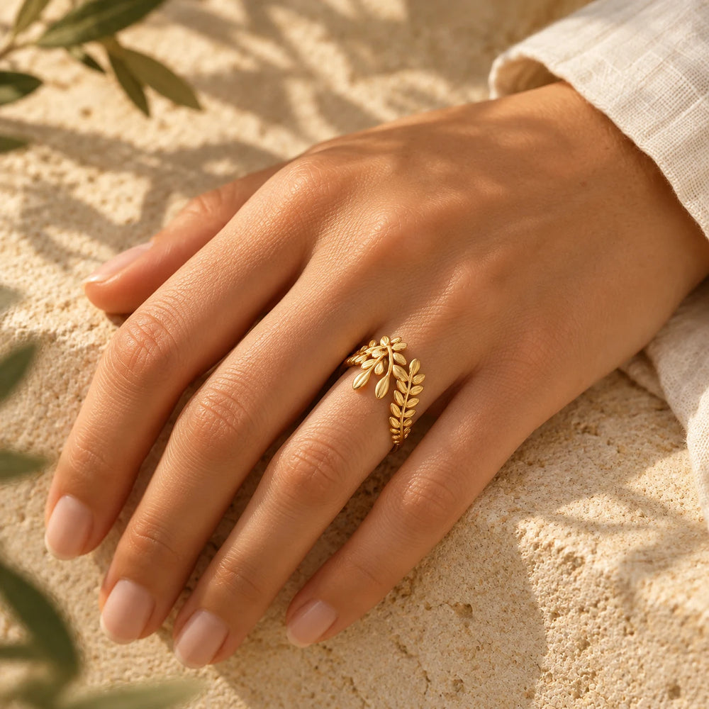 Gold-tone woven ring worn on a woman's hand on cream linen