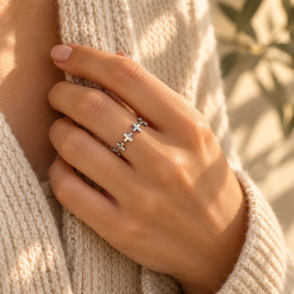 Silver-tone band of crosses ring on a woman's hand touching her collar — true size: the band is a single row of tiny crosses 6 mm tall, the ring about 20 mm across