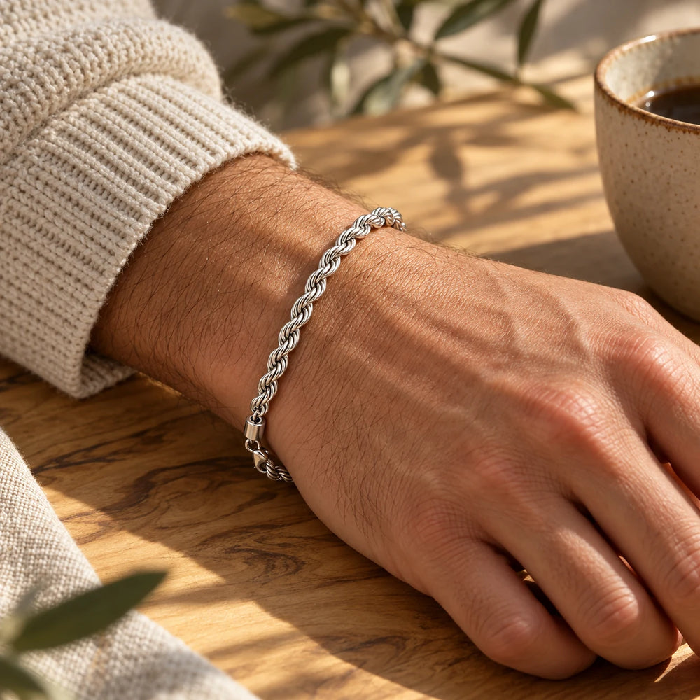 Silver-tone 5 mm rope chain bracelet on a man's wrist on an olive-wood table — true size: the twisted rope bracelet is 5 mm thick, 21 cm long
