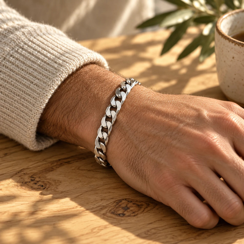 Silver-tone 8 mm cuban chain bracelet on a man's wrist on an olive-wood table — true size: the flat curb bracelet is 8 mm wide with 2 mm wire, 21 cm long