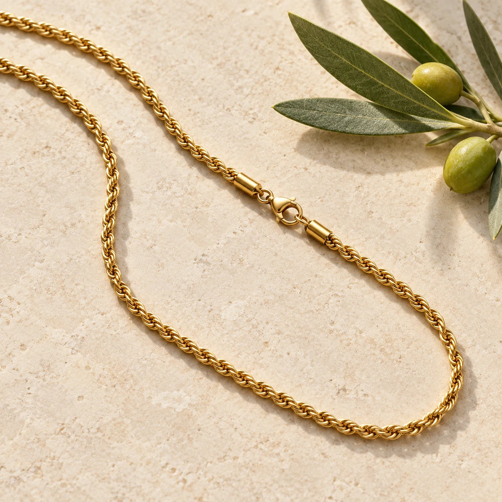 Gold-tone 3 mm rope chain necklace on a pale limestone background, with an olive sprig for scale — true size: the rope chain is 3 mm thick