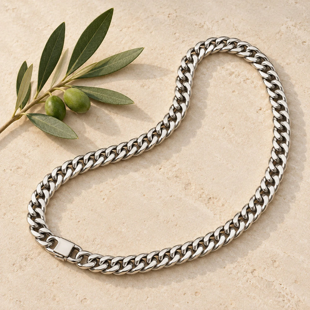 Silver-tone 8 mm cuban chain necklace on a pale limestone background, with an olive sprig for scale — true size: the heavy cuban chain is 8 mm wide and about 1.8 mm thick