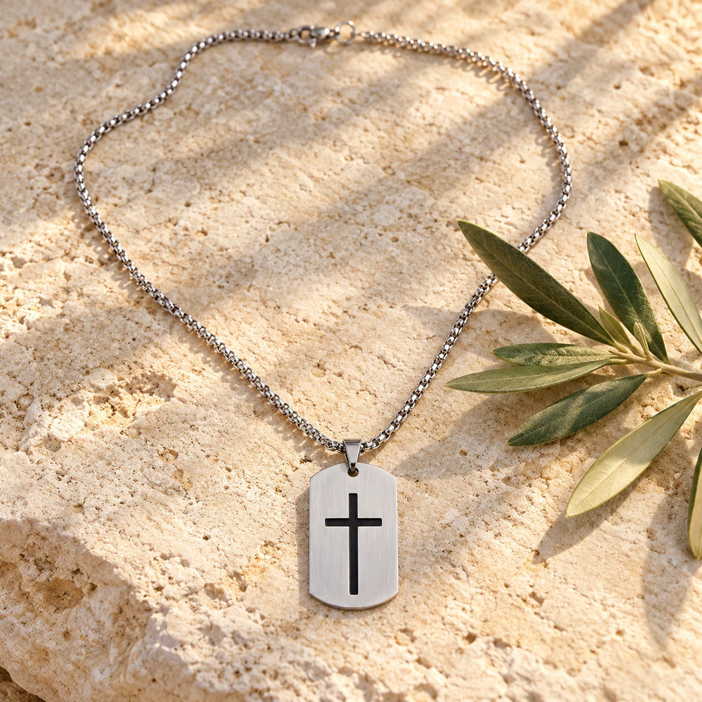 Silver-tone cross tag pendant on a box chain on a pale limestone background, with an olive sprig for scale — true size: the tag is 40 mm tall and 24 mm wide (about 49 mm with the bail), on a box chain about 2.5–3 mm wide