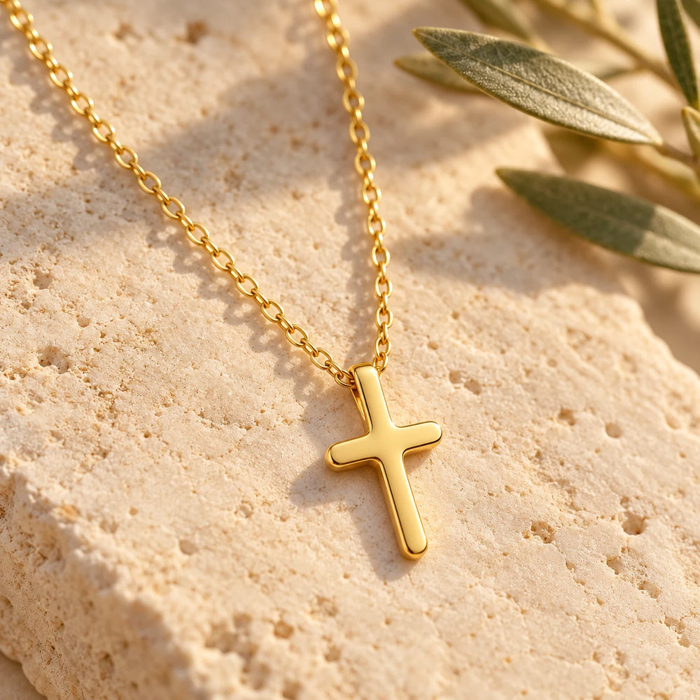 Close-up of the gold-tone tiny cross on limestone beside olive leaves