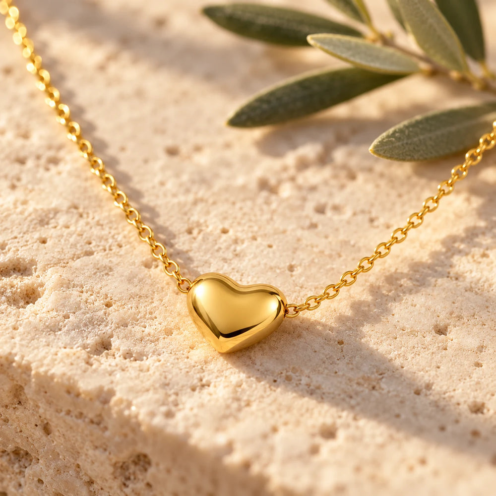 Close-up of the gold-tone puffed heart on limestone beside olive leaves