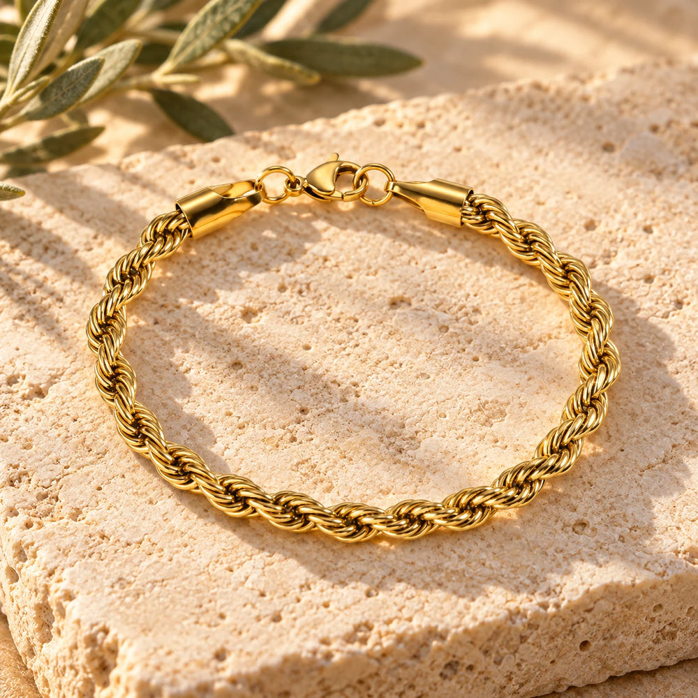 Close-up of the gold-tone 5 mm rope chain bracelet on limestone beside olive leaves