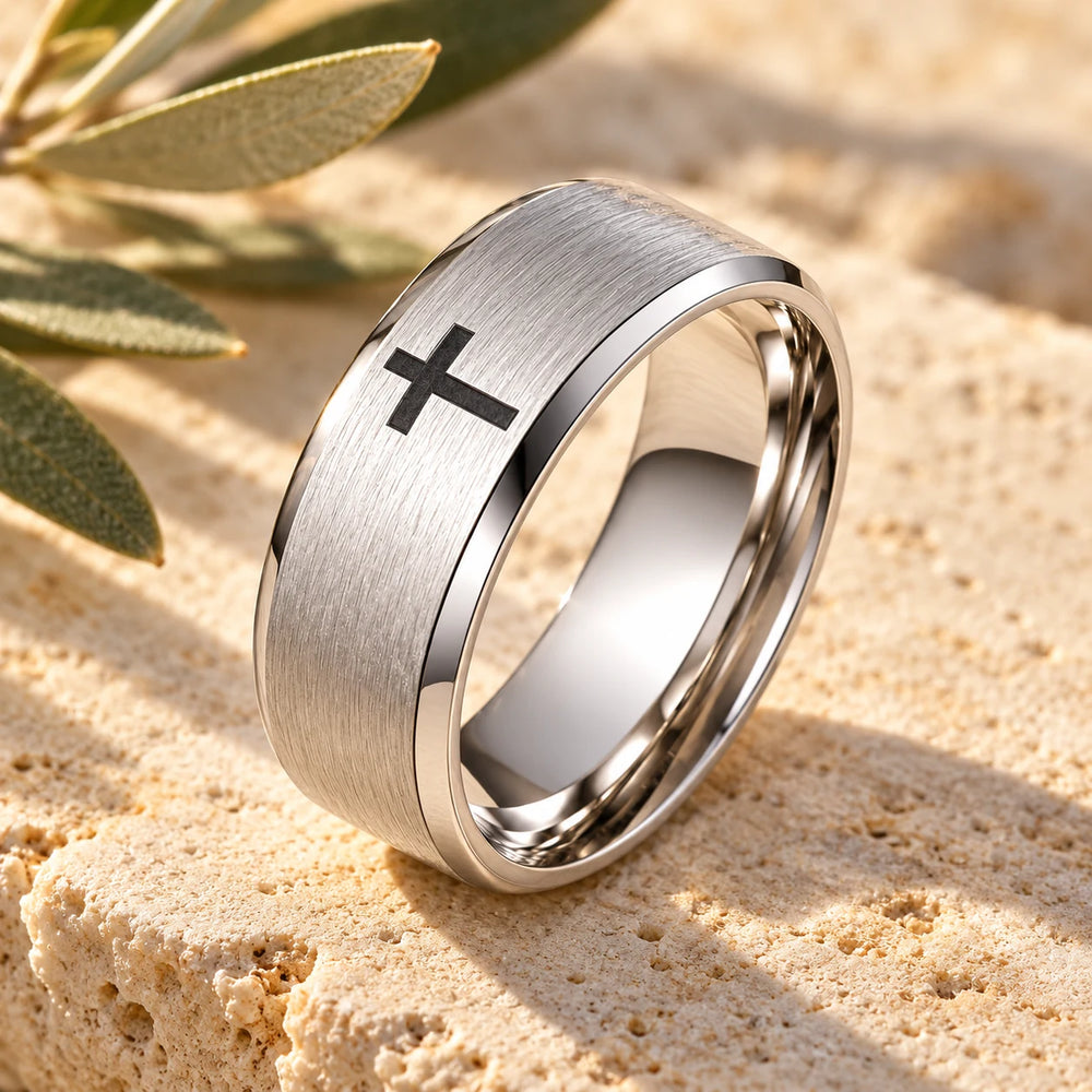 Close-up of the silver-tone cross band ring on limestone beside olive leaves