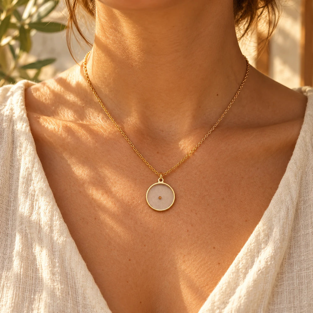 Gold-tone polished cross pendant on a box chain worn with an open linen shirt
