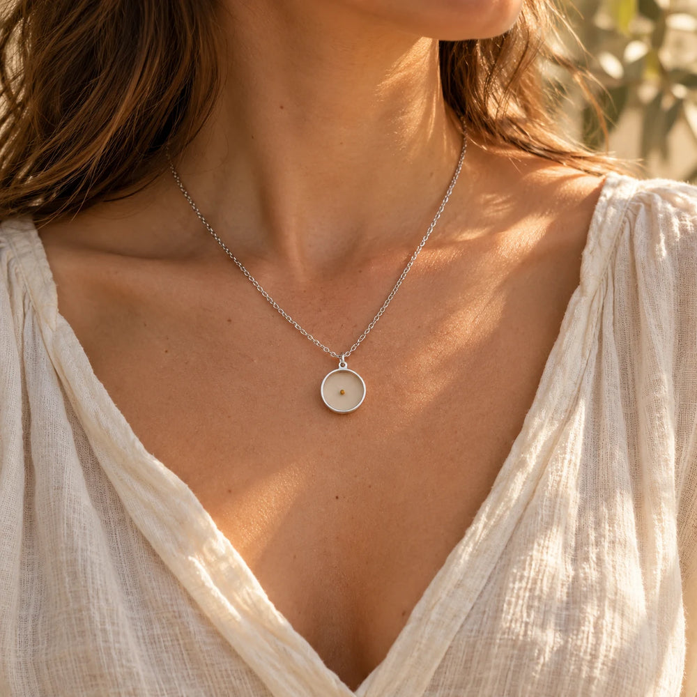 Silver-tone polished cross pendant on a box chain worn over a white t-shirt