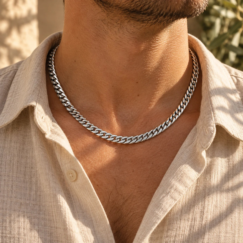 Silver-tone 6 mm cuban chain necklace worn at the collarbone with an open linen shirt — true size: the dense cuban chain is 6 mm wide